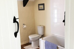 A small bathroom with a toilet, a white bathtub, and a white sink. - Courtyard Cottage With hot tub and Walled Garden (Milford Haven)