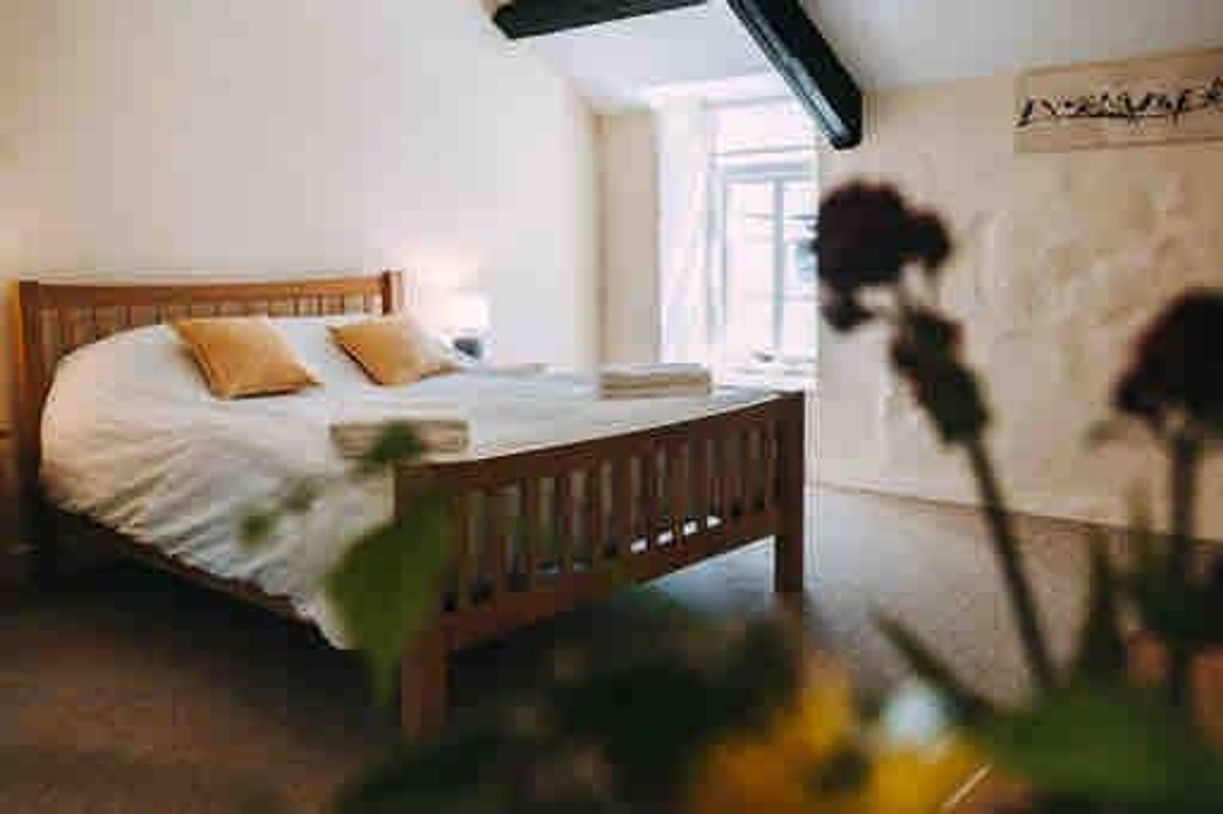 A bedroom with a wooden bed, white linens, and a single window.