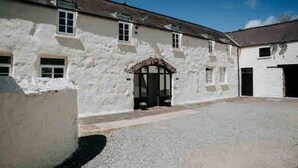 A white building with a central arched entrance, multiple windows, and a flat roof.