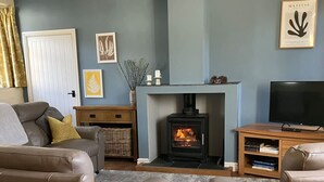 A living room with a fireplace, leather sofas, a television, and a dining table with flowers.