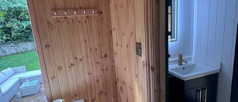 Une cabane en bois comprenant un coin repas, une petite cuisine et une vue sur l’extérieur.