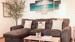 Un salon moderne avec un canapé d’angle, une table basse et une plante.