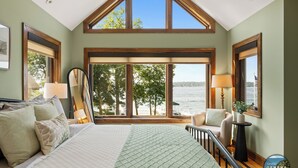 Un dormitorio con una cama grande, vistas al lago y un balcón con barandilla.