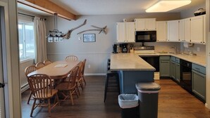 Una cocina acogedora con armarios de madera, una isla central y un comedor con mesa y sillas de madera.