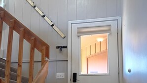 Una escalera con barandas de madera que lleva a una puerta blanca con un ventanal arriba.