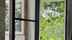A room with a window revealing a lush green outdoor view. - A little slice of paradise in Trégastel, Comme un petit coin de paradis à Trégastel (Trégastel)