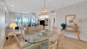 A spacious dining area with a glass-top table surrounded by wicker chairs, a ceiling fan, and a decorative hanging light fixture. - Waterfront 2BR 2BA  Pool - 10 min walk to Beach (Longboat Key)