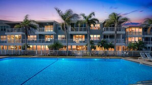 A multi-story hotel with a swimming pool, palm trees, and balconies. - Waterfront 2BR 2BA  Pool - 10 min walk to Beach (Longboat Key)