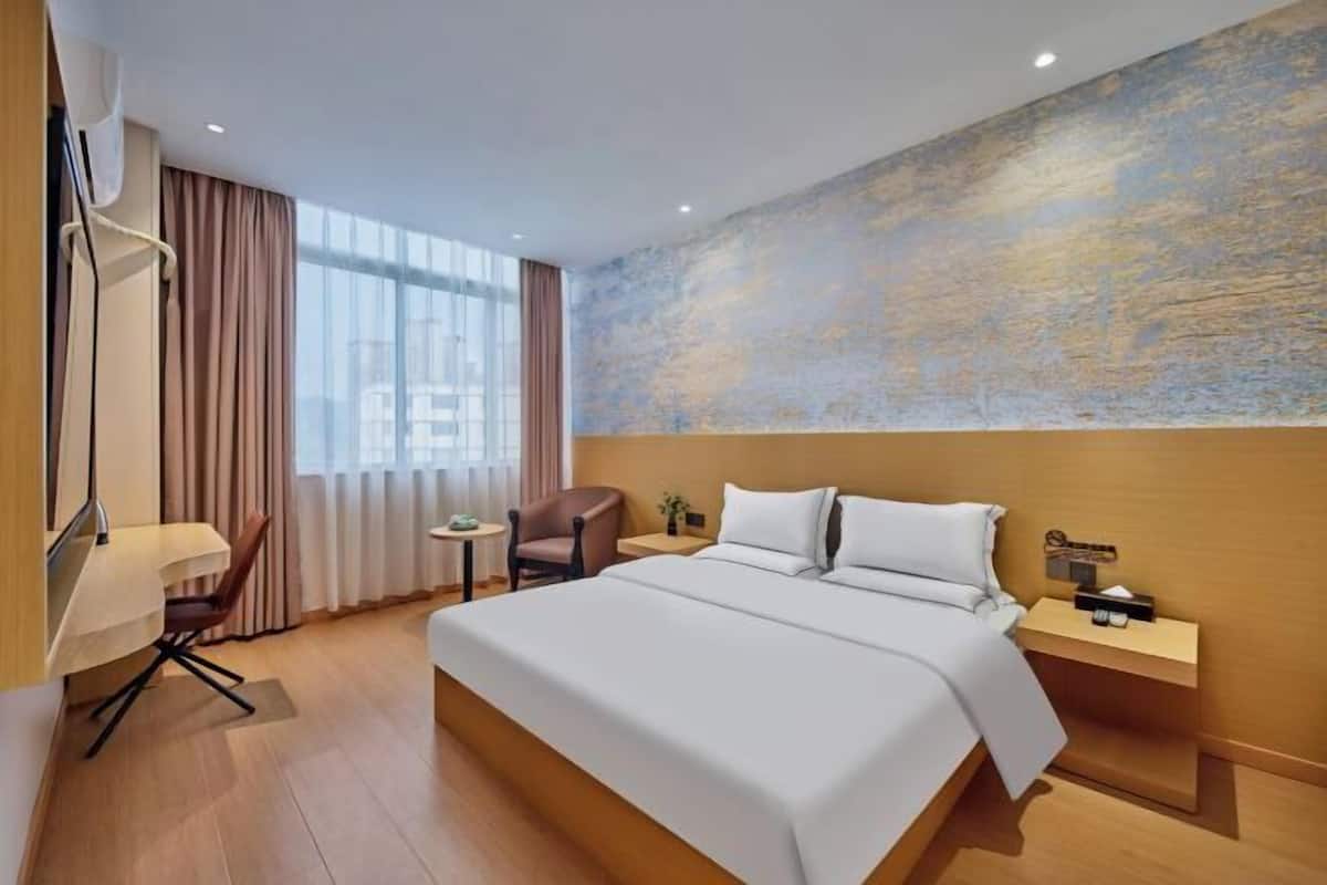 Une chambre d’hôtel avec un grand lit, un bureau, une chaise, une petite table et une table de chevet.