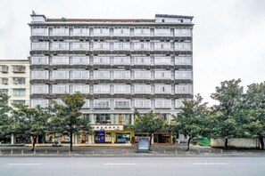 A multi-story hotel with a uniform facade, multiple balconies, and a ground-level commercial area.