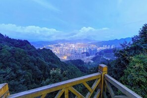 A cityscape viewed from a high vantage point with a wooden railing in the foreground. - Yiju Qingyue Hotel (Xishui)