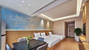 Una habitación de hotel moderna con una cama grande, una mesa de comedor y un cuadro abstracto de gran tamaño en la pared.