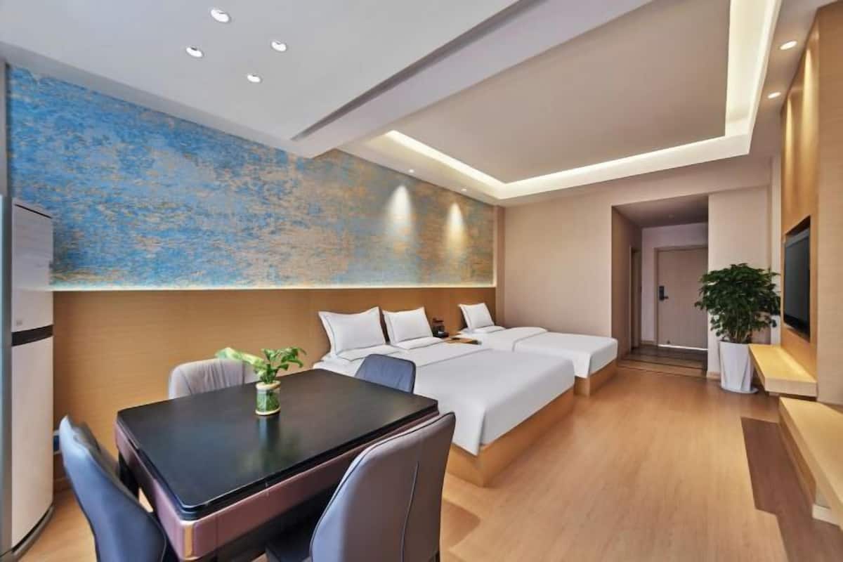 Une chambre d’hôtel moderne avec un grand lit, une table à manger et un grand tableau abstrait accroché au mur.