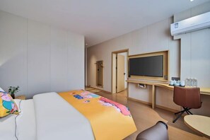 A hotel room with a bed, a desk, a chair, a TV, and a door leading to another room. - Yiju Qingyue Hotel (Xishui)