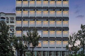 A multi-story hotel with a uniform facade, balconies, and illuminated windows. - Yiju Qingyue Hotel (Xishui)