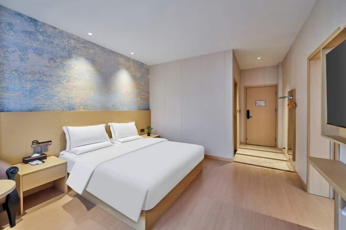 Une chambre d’hôtel moderne, dotée d’un grand lit, de tables de chevet, d’un bureau et d’une télévision.