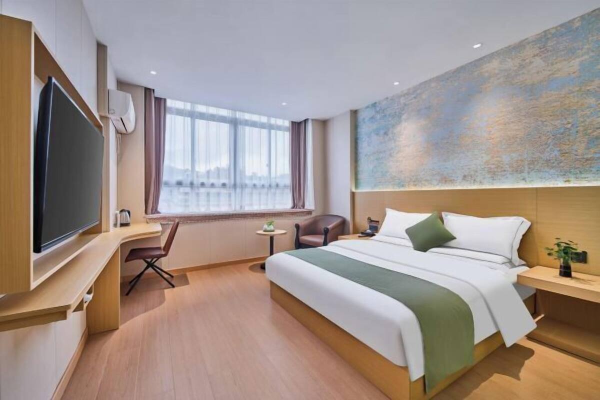 Une chambre d’hôtel moderne dotée d’un grand lit, d’un bureau, d’une télévision et d’une fenêtre offrant une vue agréable.