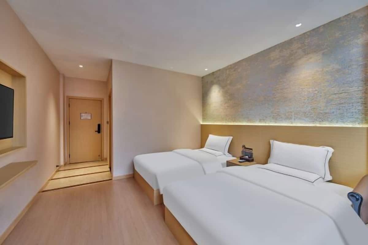 Une chambre d’hôtel avec deux lits, un téléviseur à écran plat et un mur à motifs.