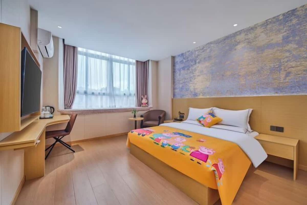 Une chambre d’hôtel avec un lit, un bureau, une chaise et une grande fenêtre.