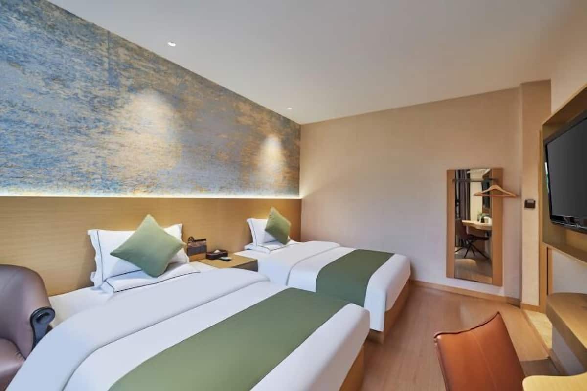 Une chambre d’hôtel avec deux lits, une télévision, un bureau et une chaise.