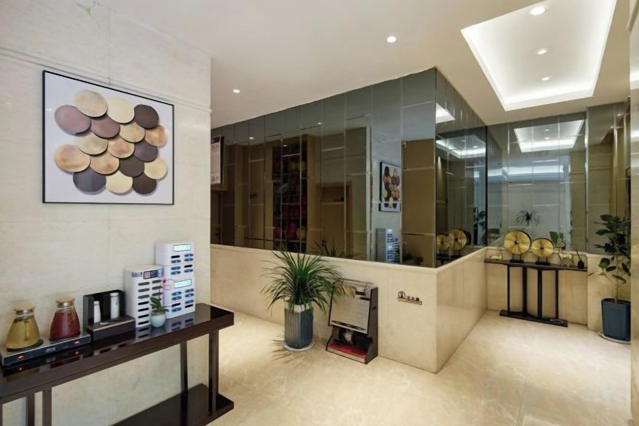 A reception area with a modern design, including a reception desk, a large mirror, and a potted plant.