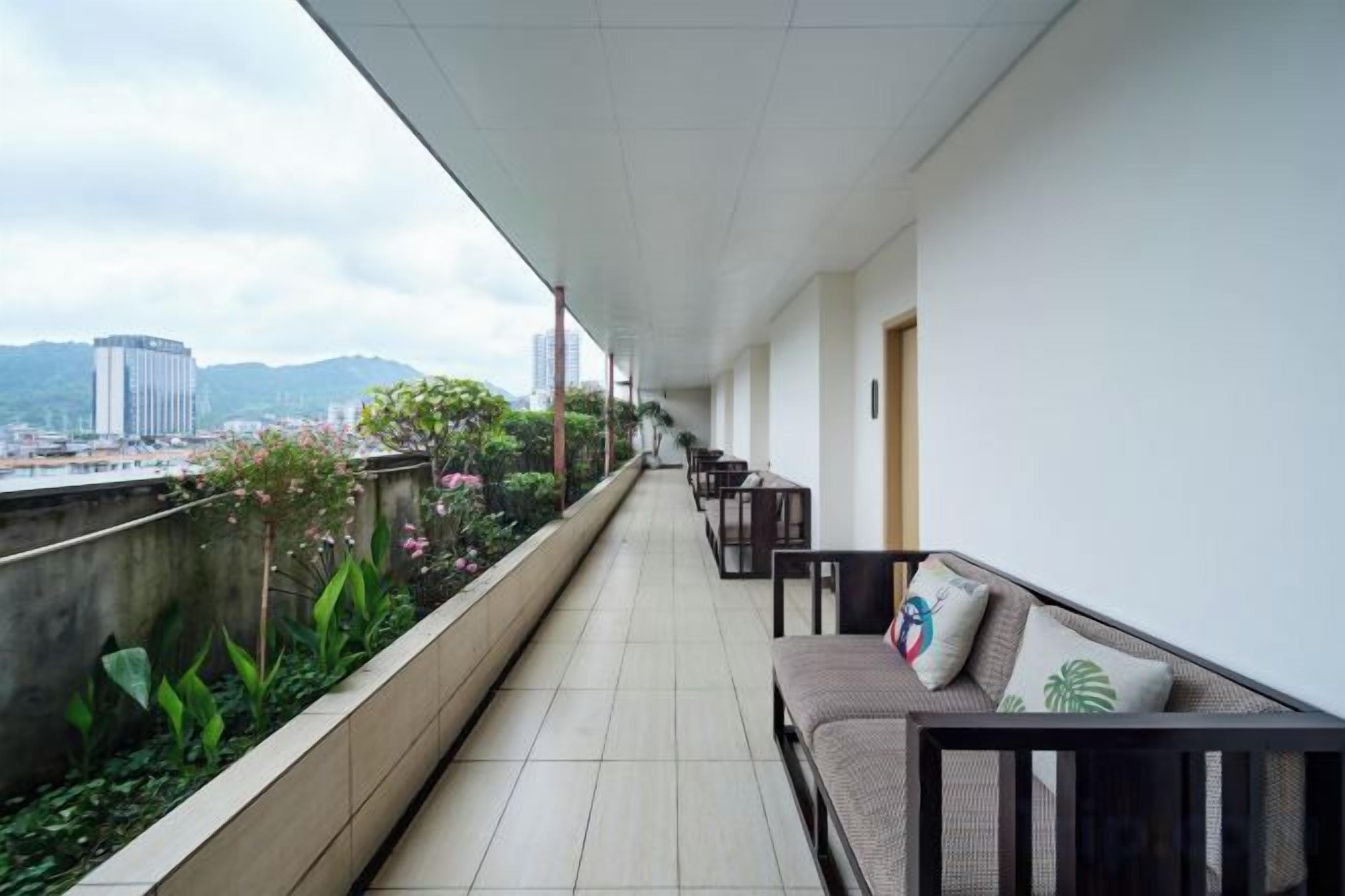 A balcony with a view of the city, a sofa with cushions, and a railing.