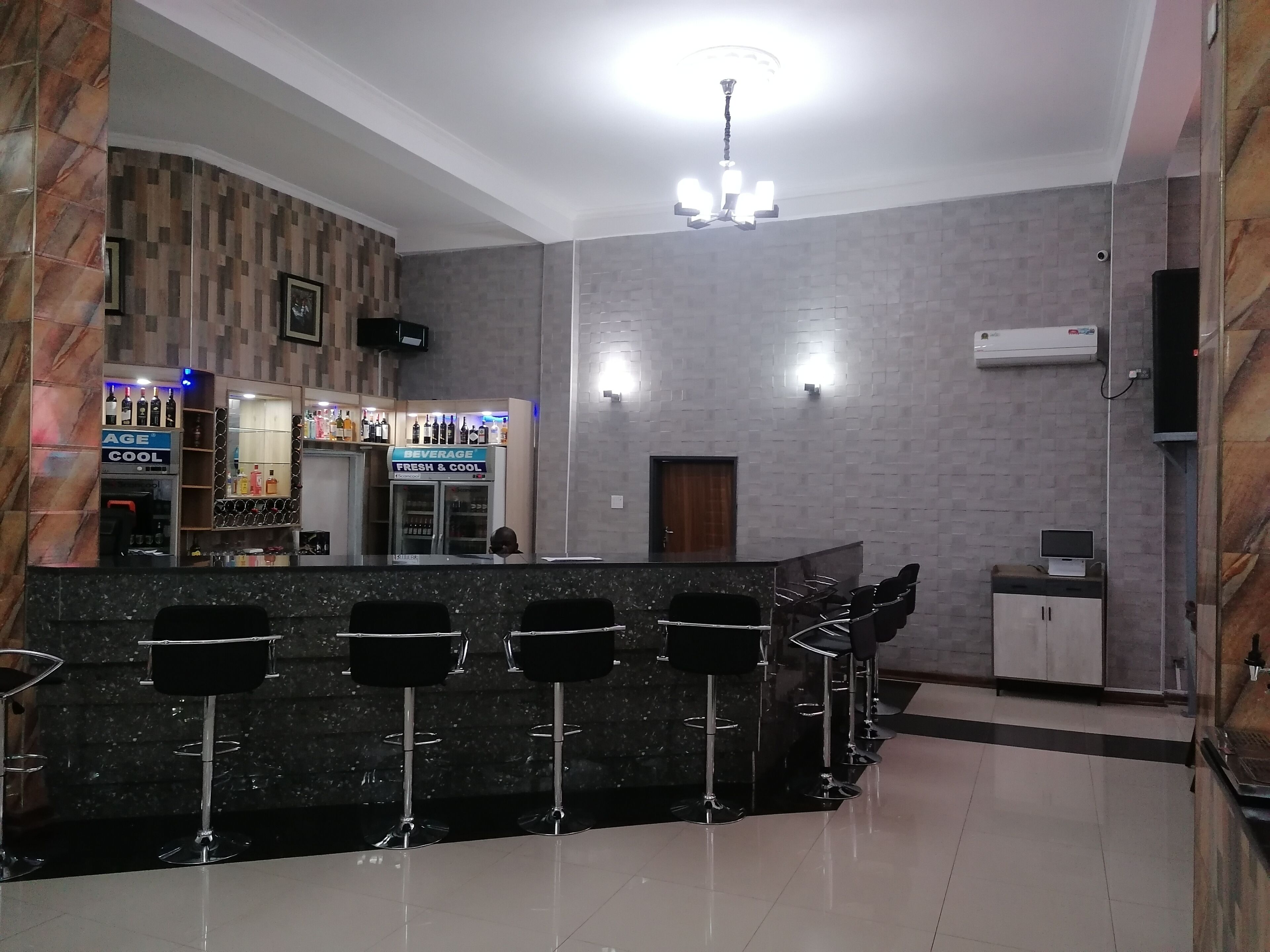 A bar area with a counter, bar stools, and a beverage sign.