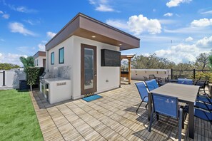 A modern outdoor patio with a wooden deck, a barbecue area, and a seating arrangement.