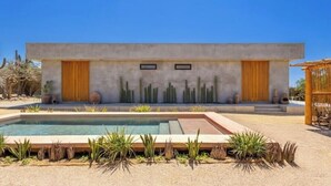 Una casa moderna con piscina, rodeada de vegetación desértica.