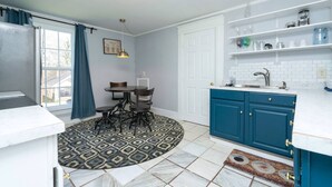 Une cuisine de taille réduite avec des meubles blancs, un plan de travail bleu et un tapis à motifs.
