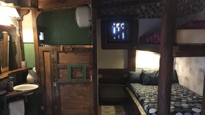 Une pièce compacte avec un lit superposé, une petite kitchenette et un mur vert.