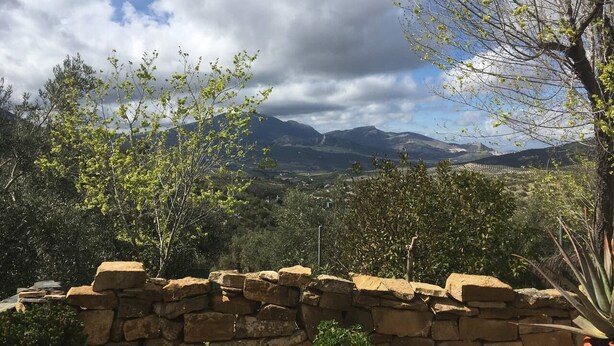 Un mur de pierre offrant une vue sur une vallée et, au loin, sur des montagnes.