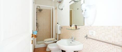 Een badkamer met toilet, bidet, wastafel en spiegel.
