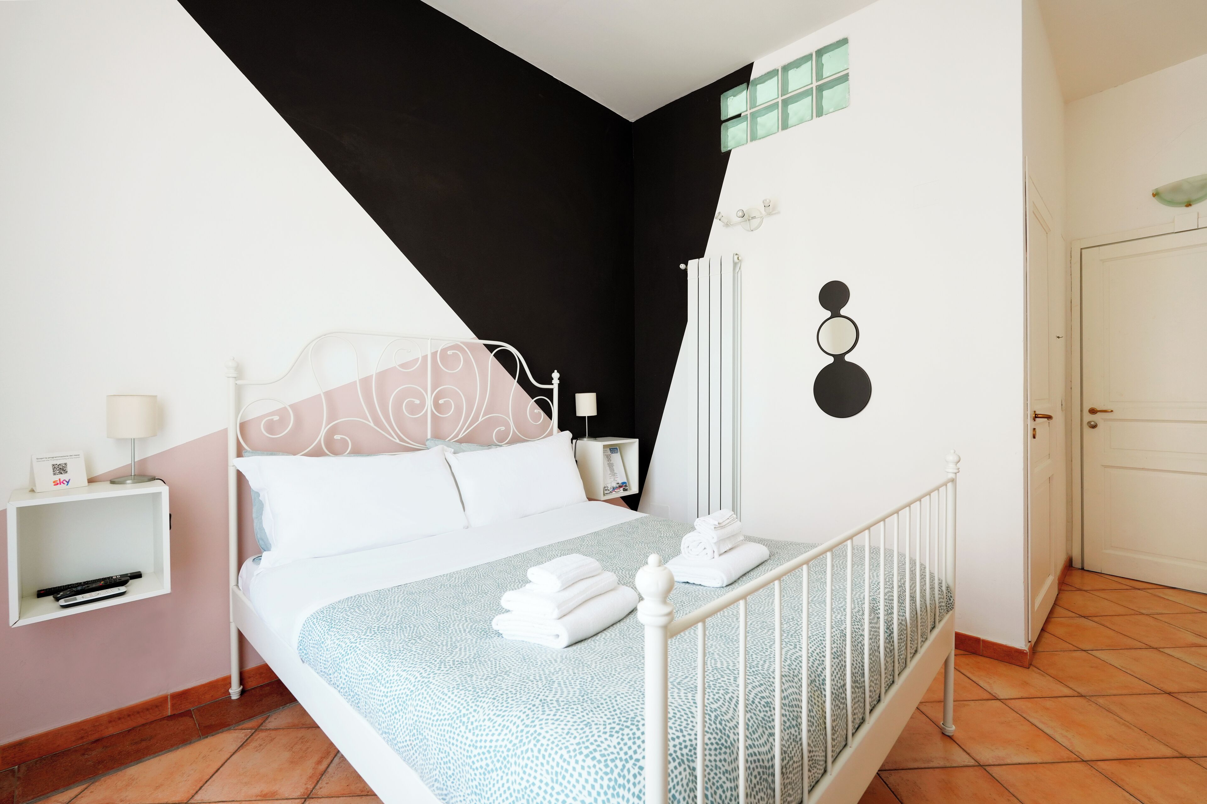 A neatly arranged bedroom with a bed, bedside table, and a wall-mounted radiator.
