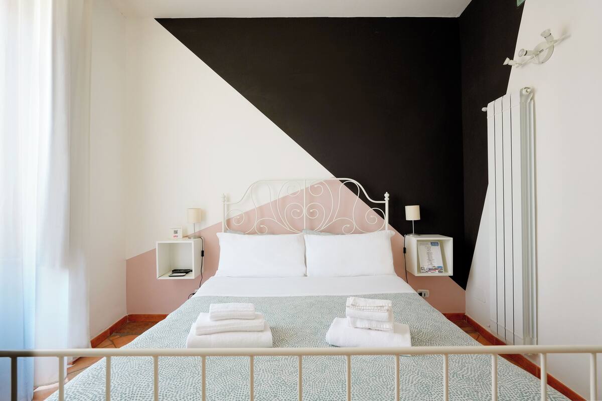 A modern hotel room with a bed, bedside tables, and a radiator.