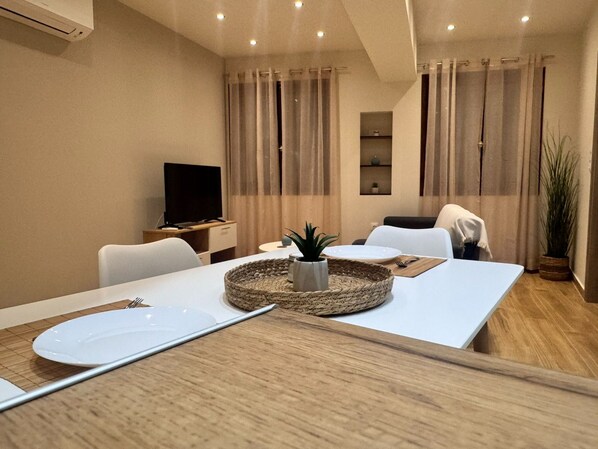 Une chambre d’hôtel moderne dotée d’un coin repas, d’une télévision et d’une plante en pot.