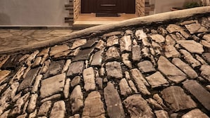 A stone-paved entrance with a wooden door and a light above it. - Milies Creekside Studio (South Pelion)