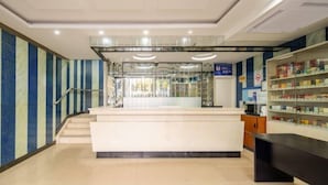 A reception area with a counter, a staircase, and a pharmacy. - Nalan Hotel (Shanghai)