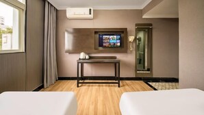 A hotel room with two beds, a TV mounted on the wall, a bedside table, and a mirror. - Nalan Hotel (Shanghai)