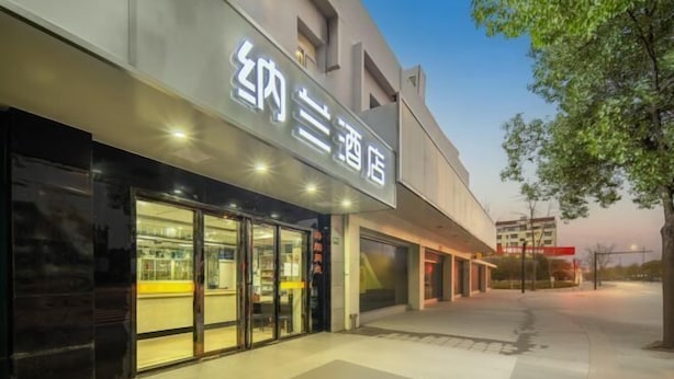 A modern hotel entrance with a large sign, glass doors, and a paved walkway. - Nalan Hotel (Shanghai)