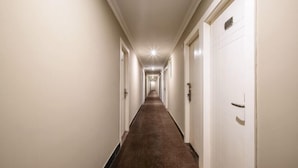 A long, narrow hallway with white walls and a brown carpet. - Nalan Hotel (Shanghai)