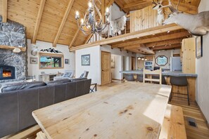 A spacious living area with a stone fireplace, wooden ceiling, and a large dining table. - The Lincoln Lodge - Spacious Bitterroot Valley Retreat Between Hamilton & Victor (Victor)