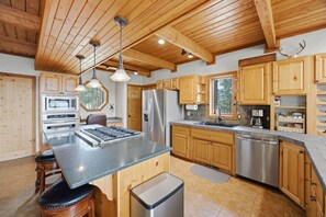 A modern kitchen with wooden cabinets, stainless steel appliances, and a central island. - The Lincoln Lodge - Spacious Bitterroot Valley Retreat Between Hamilton & Victor (Victor)
