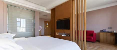 Una habitación de hotel con una cama grande, un televisor montado en la pared, una silla roja y un panel de madera.