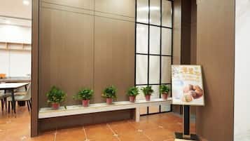 A reception area with a bench, potted plants, and a signboard.