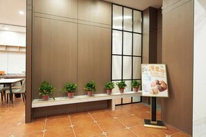 A reception area with a bench, potted plants, and a signboard.