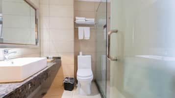 Un baño moderno con cabina de ducha de vidrio, un lavabo blanco y un inodoro.