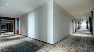Un pasillo de hotel con alfombra estampada, paredes blancas y un camino recto hasta el final.