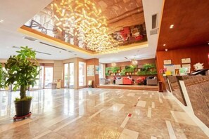 A spacious lobby with a high ceiling, a reception desk, and a large potted plant. - Yiju Fashion Hotel (Wuwei Railway Station Pedestrian Street) (Wuwei)
