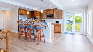 A modern kitchen with wooden cabinets, a central island, and bar stools. - Ocean front paradise in Little Torch Key (Little Torch Key)